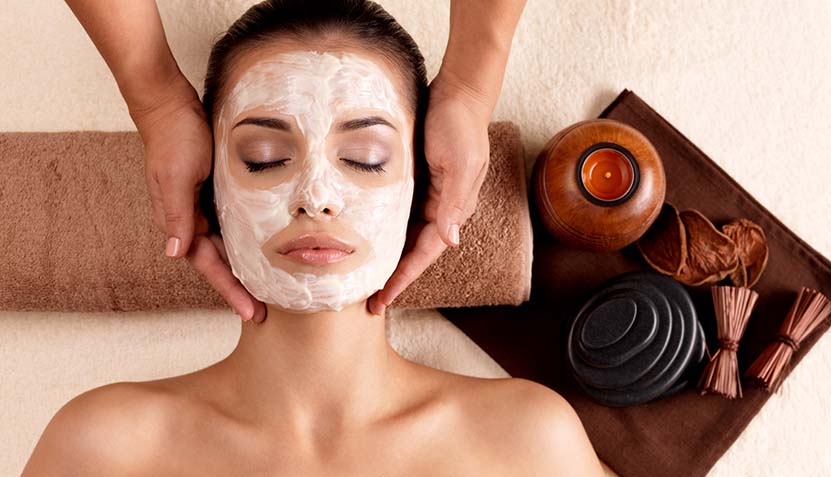 Spa massage for woman with facial mask on face